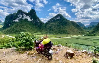 a motorcycle parked on a dirt road near a mountain in Vietnam