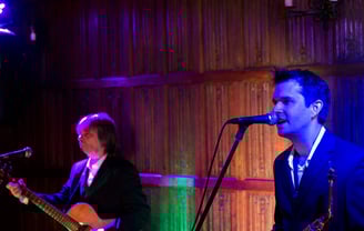 men in a suits playing guitar and saxophone
