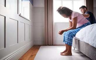 a man and woman sitting on a bed in health behaviour change