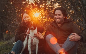 ragazza e ragazzo con cane al tramonto