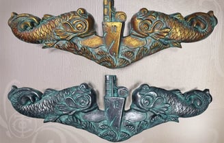 Pic of a gold Submarine Warfare Insignia Officers dolphins over a silver Enlisted dolphin sculpture. 