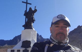 a man in a white shirt and a cross - country Cristo Redentor Andes Chile