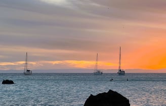 a sunset with sailboats in the water