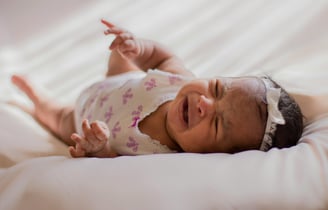 a baby girl crying in a bed
