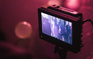 Behind-the-scenes shot of a film set, featuring a monitor displaying actors in action