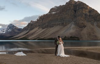 a bride and groom standing in front of Bow Lake in Banff