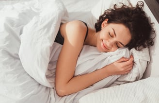 a woman is sleeping in a bed with a blanket
