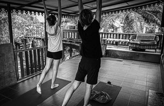 A man and woman practising yoga on a wooden veranda