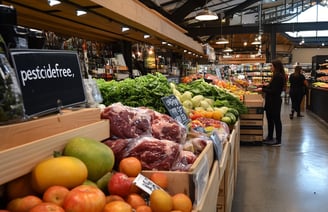a man standing in a store with a lot of fruit and vegetables