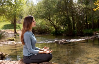 An individual meditating in a serene environment.