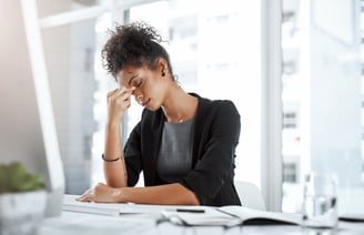 a woman sitting at a desk with a laptop and a notebook