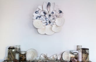 a seashell mandala above a shelf with more seashells