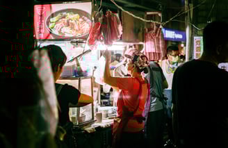 a woman is standing in front of a food vendor in Taiwan
