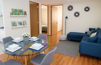 Interior de departamento muestra con comedor y sala modernos, piso laminado, sofá azul, decoración