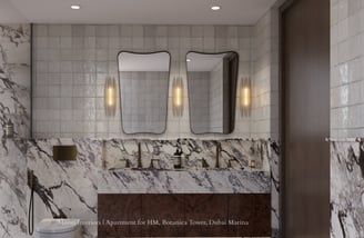 Marble-clad bathroom with two distinct mirrors and gold fixtures.