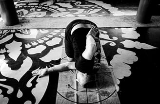 A man practices thread the needle pose in a yoga studio