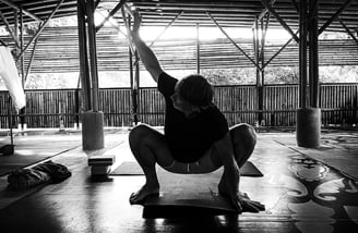 A man executes a squat during yoga class.