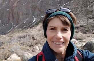 Susan Rensberger in the rugged Andes mountains wearing a headband and sunglasses on her head