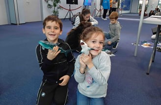 2 enfants avec des maquettes requins dans la main qui sourient
