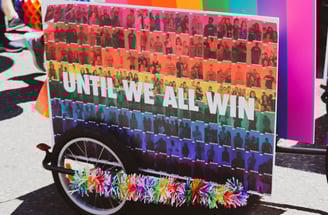 A wagon holding a rainbow sign that says "UNTIL WE ALL WIN"