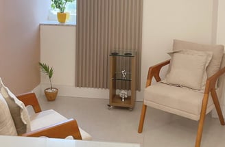 Foto do consultório de psicologia da psicóloga Laura Maria, duas poltronas e fundo de madeira.