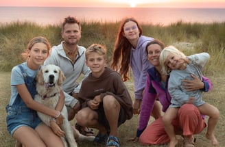 Famille nomade (2 adultes, 4 enfants, chien) voyageant en van sous un coucher de soleil. Paysage pai