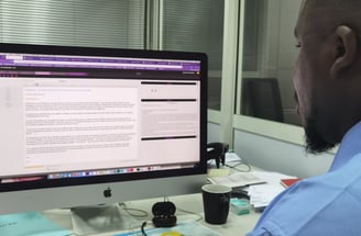 a man sitting at a desk with a computer monitor and a laptop