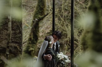 a bride and groom kissing on a bridge