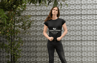 a woman in a black shirt and jeans standing in front of a wall