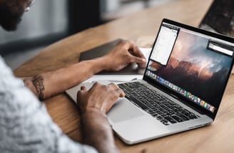 person using macbook pro on white table