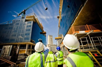 two men in safety vests standing in front of a building