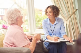 a woman in a blue shirt is sitting on a couch doing a care assessment