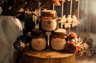 three coffee scented candles in amber glass jars stacked on top of each oither