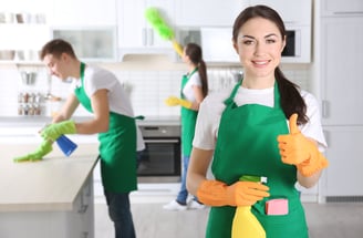 a woman in green aprons holding a cleaning sponge