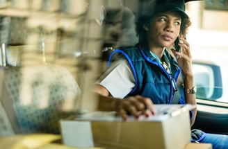 a woman in a blue vest and hat talking on the phone