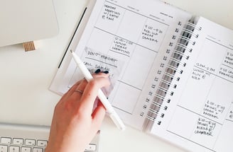 a person holding a pen and writing on a notebook