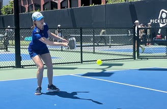 Woman hitting a backhand shot during outdoor pickleball play at a Smart Dinker session.