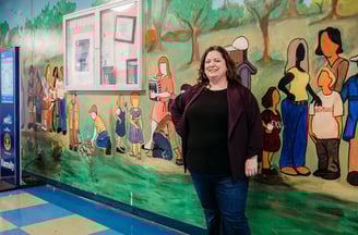 Woman in purple sweater standing in front of painted mural