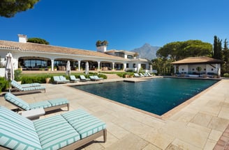 Expansive pool terrace at Villa La Gratitud, with sun loungers, covered porches, and mountain views.