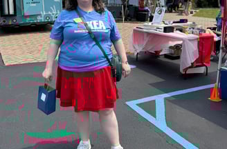 Woman in KEA tshirt standing in front of booths at the public library cultural pass kickoff