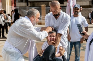 a man in a white shirt is being helped by a man in a wheelchair