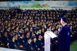 Um homem em uma beca de formatura falando em um microfone
