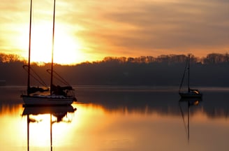 a sailboat is shown in the foreground of a sunset