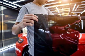 a man in a gray shirt is holding a bag of black paper