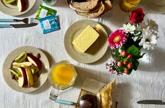 Brunch gourmand avec viennoiseries, fruits frais et fleurs, servi dans une location de charme