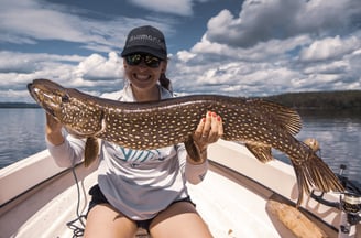 Girl angler proudly posing with her personal best catch, a pike.