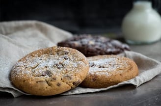 two cookies and a milkshake in a glass jar