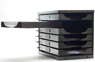 A black and white image of a set of documents drawers with one open drawer
