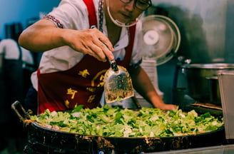 a man in a red apron making Taiwanese Oyster Omelette