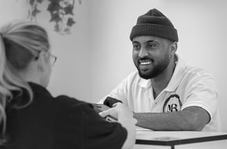 Black and White image of barber tending to customer who wants to pay at the front desk